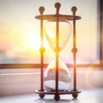 An hour glass with the sun setting behind it