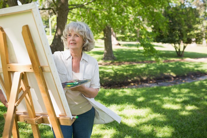 Senior woman painting in a park on a sunny day