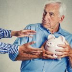 senior man holding piggy bank suspicious protecting savings