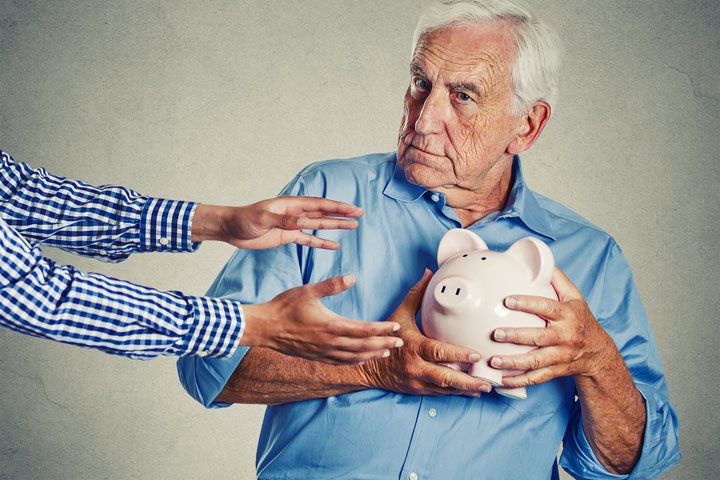 senior man holding piggy bank suspicious protecting savings