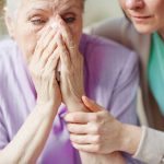 senior woman sad with adult caregiver