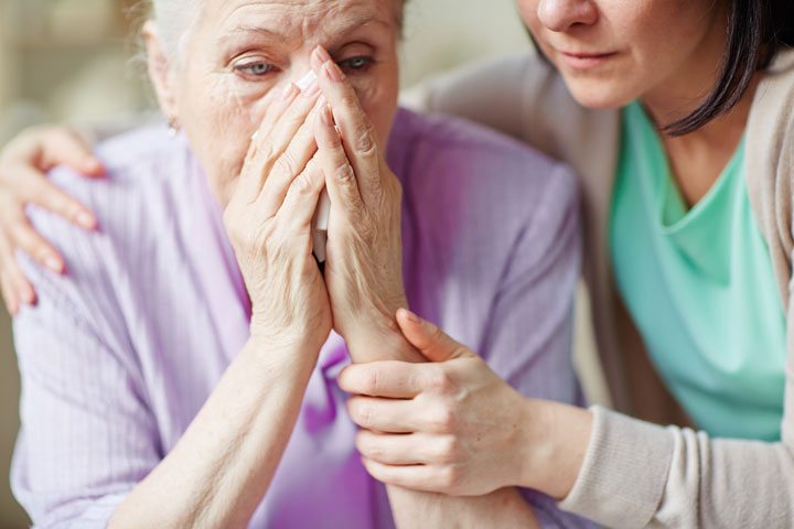 senior woman sad with adult caregiver