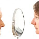 An older woman and a younger woman looking in the mirror