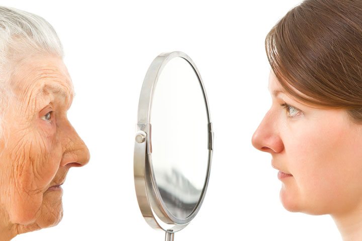 An older woman and a younger woman looking in the mirror