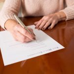 Senior woman signing a contract/will at home