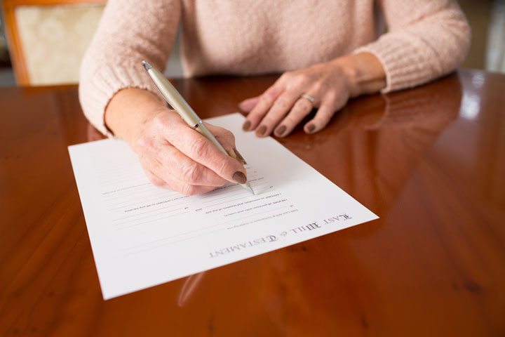 Senior woman signing a contract/will at home