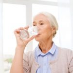 happy senior woman with glass of water at home