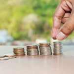 Close up of hand stacking silver coins on wooden table