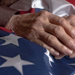 A seniors' hands atop an American flag