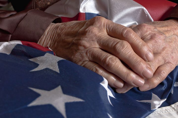 A seniors' hands atop an American flag