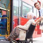 Driver Helping Senior Couple Board Bus Via Wheelchair Ramp