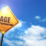 Yellow road sign with a blue sky and white clouds: age discrimination