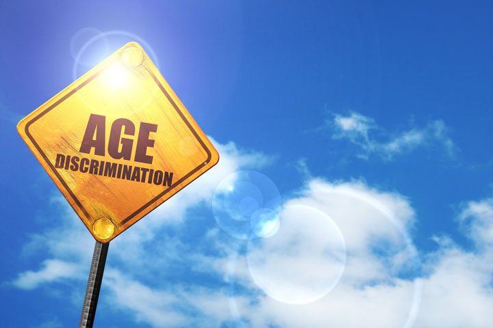 Yellow road sign with a blue sky and white clouds: age discrimination