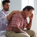 Adult Son Comforting Father Suffering With Dementia