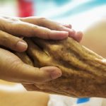 Young hand holding older person's hand