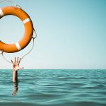 a person's hand reaching out from the sea asking for a float