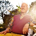 happy senior man sitting in sun light in garden