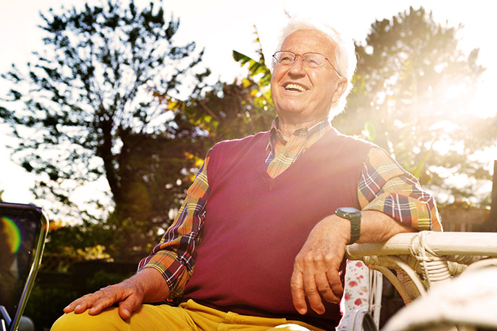 happy senior man sitting in sun light in garden