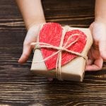 Children's hands hold gift box on a wooden table-top.A concept by the Mother's Day. Vintage toning. Father's day. Birthday.