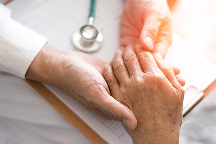 A healthcare worker holding the hand of an elderly patient.