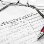 Medicare enrollment form with a pen and a pair of glasses on top. Form has not yet been filled in.