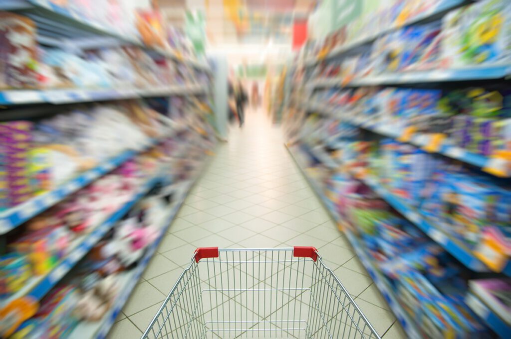 Shopping cart in a grocery food aisle from perspective of shopper .