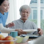 caretaker serving a healthy breakfast to an older gentleman.