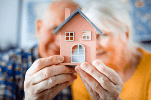 An older couple holding a model of a house.