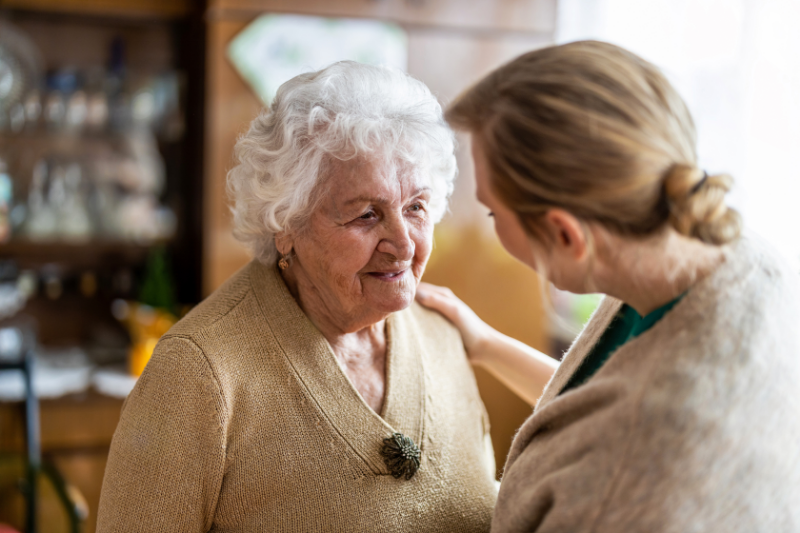 Caregiver offering support to an older female dementia patient